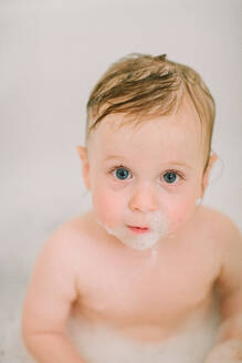 Nahaufnahme eines Babys in der Badewanne mit Blasen im Gesicht - CAVF81561