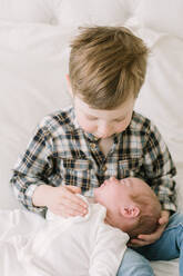 Big brother hold baby sister for first time on bed - CAVF81568