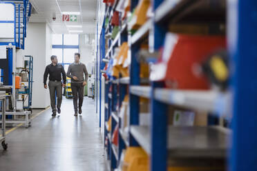 Two men walking and talking in factory - DIGF10936