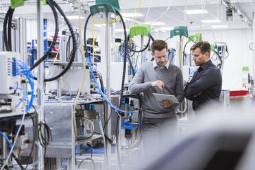 Two men using tablet in factory - DIGF10937