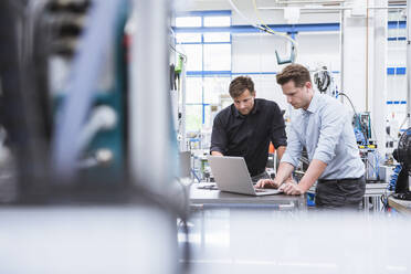 Zwei Männer benutzen einen Laptop in einer Fabrik - DIGF10943