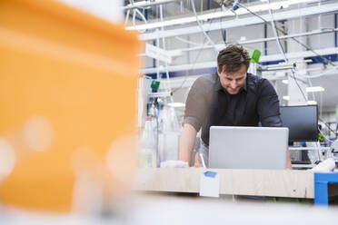 Mann mit Laptop in einer Fabrik - DIGF10945