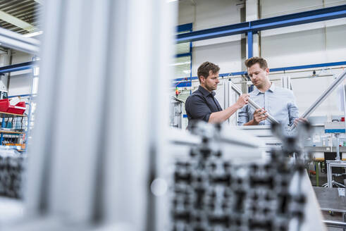Zwei Männer bei einer Besprechung in einer Fabrik, die ein Produkt untersucht - DIGF10952