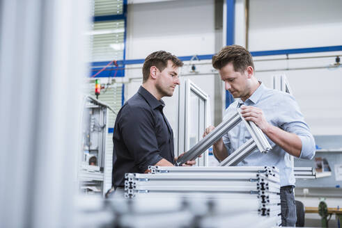 Zwei Männer bei einer Besprechung in einer Fabrik, die ein Produkt untersucht - DIGF10953