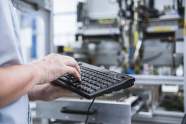 Close-up of man using keyboard in factory - DIGF10955