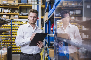 Man with clipboard taking notes in factory - DIGF10968