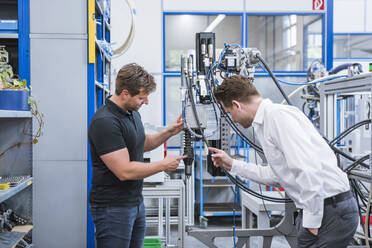 Zwei Männer bei einer Besprechung an einer Maschine in einer Fabrik - DIGF10969