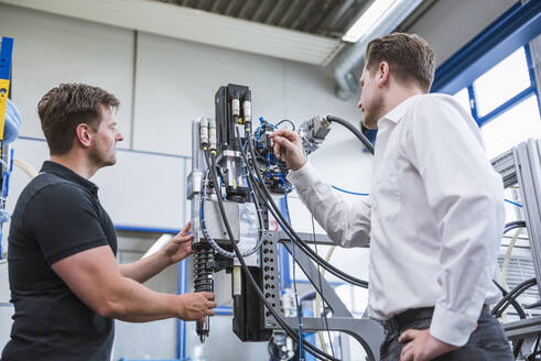 Zwei Männer bei einer Besprechung an einer Maschine in einer Fabrik - DIGF10970
