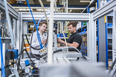 Zwei Männer bei einer Besprechung an einer Maschine in einer Fabrik - DIGF10972