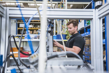 Mann bedient eine Maschine in einer Fabrik - DIGF10973