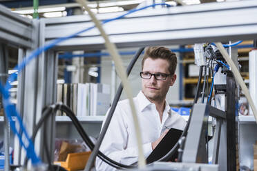 Man with clipboard taking notes in factory - DIGF10974