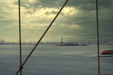 USA, New York, New York City, East River bei dramatischer Morgendämmerung mit Liberty Island im Hintergrund - LOMF01125