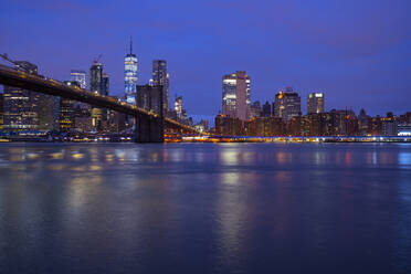 USA, New York, New York City, East River und Brooklyn Bridge in der lila Morgendämmerung mit der Skyline von Manhattan im Hintergrund - LOMF01129