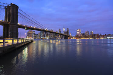 USA, New York, New York City, East River and Brooklyn Bridge at purple dawn with Manhattan skyline in background - LOMF01131