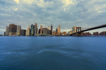 USA, New York, New York City, East River and Brooklyn Bridge at dawn with Manhattan skyline in background - LOMF01132