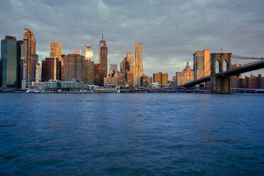 USA, New York, New York City, East River and Brooklyn Bridge at dawn with Manhattan skyline in background - LOMF01133