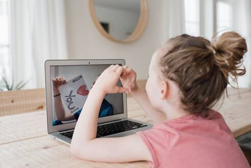 Girl talking to a nurse on a video call with an I love you sign - CAVF81870