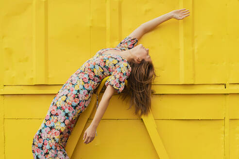 Woman in flower dress bending over attachment of yellow container - ERRF03825