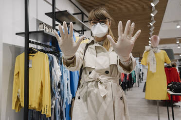 Woman with face mask and disposable gloves shopping in a fashion store - AHSF02586