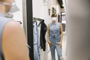 Woman with face mask trying on clothes in a fashion store - AHSF02597