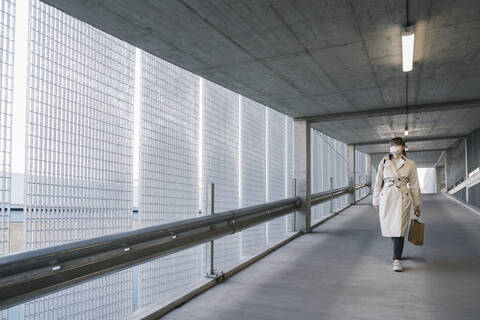 Woman wearing face mask walking in corridor of a car park after shopping stock photo