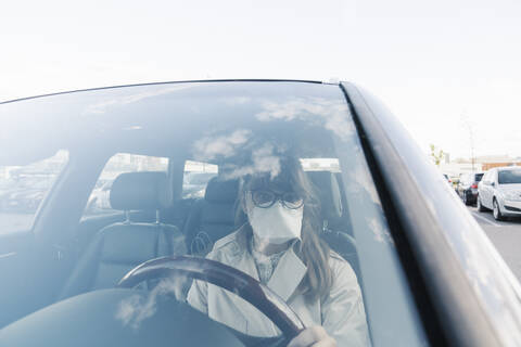 Frau mit Gesichtsmaske in einem Auto, lizenzfreies Stockfoto