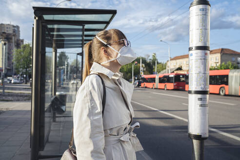 Woman wearing face mask checking schedule of public transport in the city - AHSF02614