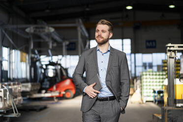 Young businessman with tablet walking in a factory - DIGF10979