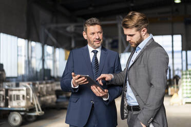 Two businessmen with tablet having a meeting in a factory - DIGF10984