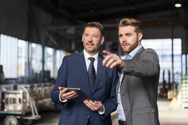 Two businessmen with tablet having a meeting in a factory - DIGF10985