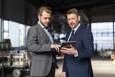 Two businessmen with tablet having a meeting in a factory - DIGF10986