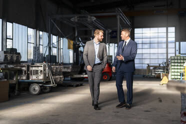 Two businessmen walking and talking in a factory - DIGF10988
