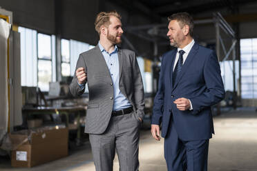 Two businessmen walking and talking in a factory - DIGF10989