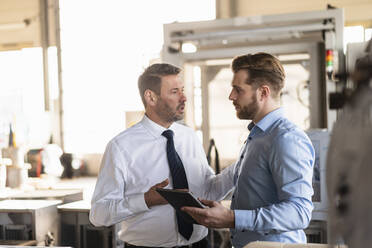 Two businessmen with tablet having a meeting in a factory - DIGF11008