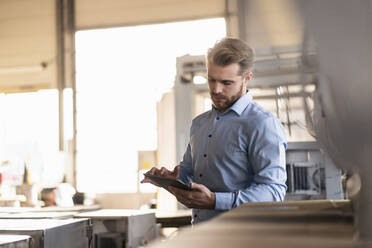 Young businessman using tablet in a factory - DIGF11010