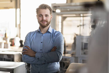 Portrait of a confident young businessman in a factory - DIGF11013