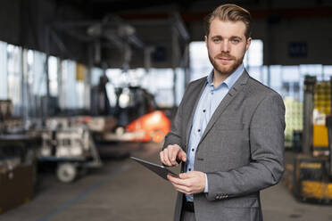 Porträt eines selbstbewussten jungen Geschäftsmannes mit Tablet in einer Fabrik - DIGF11032
