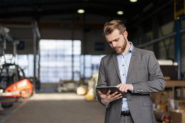 Junger Geschäftsmann benutzt Tablet in einer Fabrik - DIGF11033