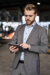 Junger Geschäftsmann benutzt Tablet in einer Fabrik - DIGF11035