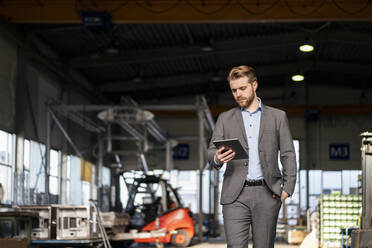 Young businessman using tablet in a factory - DIGF11037