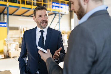 Two businessmen having a meeting in a factory discussing workpiece - DIGF11048