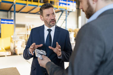 Two businessmen having a meeting in a factory discussing workpiece - DIGF11049