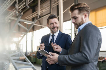 Two businessmen with tablet having a meeting in a factory - DIGF11070