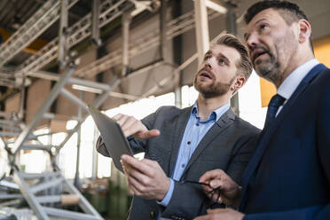 Two businessmen with tablet having a meeting in a factory - DIGF11073