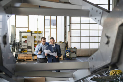 Zwei Geschäftsleute bei einem Treffen in einer Fabrik, lizenzfreies Stockfoto