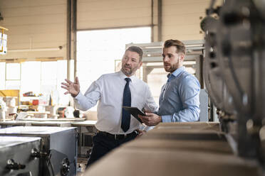 Two businessmen with tablet having a meeting in a factory - DIGF11085