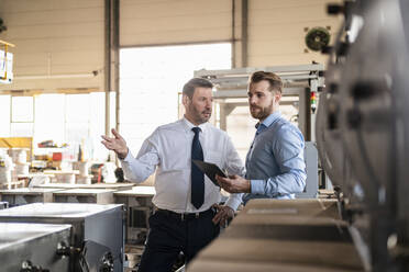 Two businessmen with tablet having a meeting in a factory - DIGF11086