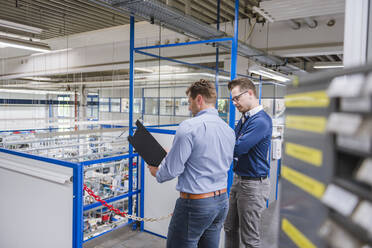 Two businessmen with clipboard in factory - DIGF11096