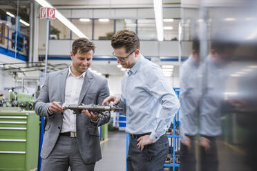 Two businessmen examining a product in a factory - DIGF11102