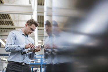 Businessman examining a product in a factory - DIGF11105